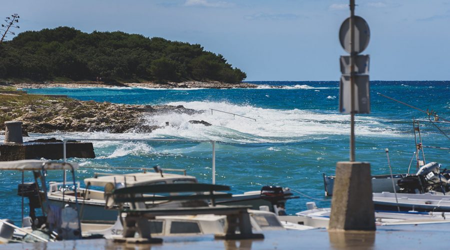 Strong winds and waves are hitting small fishing harbor. Port in Silba Croatia is experiencing bad windy weather.